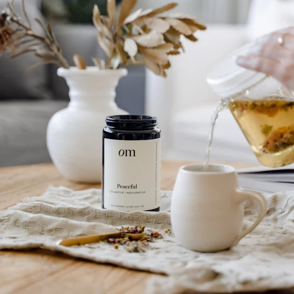 OM Peaceful Tea next to a glass teapot