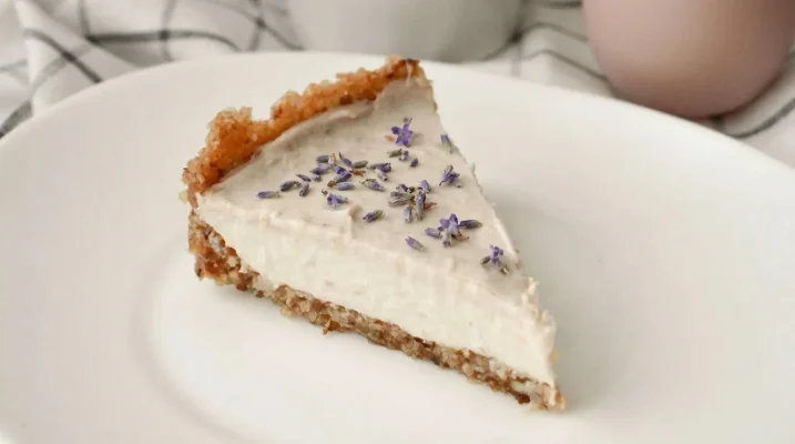 A slice of a gluten free cheesecake with lavender sprinkled on top.